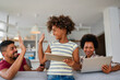 © NDABCREATIVITY - Planning vacation together. African american father, mother and daughter using computer at home,