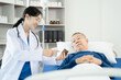 © NINENII - medicine, healthcare and people concept - doctor talking to male patient at bed in hospital.