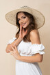 © forma82 - Very beautiful young woman in straw hat and white boho dress on creamy background.