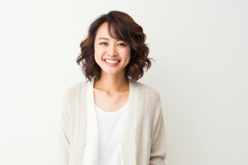 Poster - Portrait of a happy Japanese woman in her 30s wearing a chic cardigan against a white background