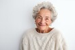 Portrait of a Israeli woman in her 90s wearing a cozy sweater against a white background