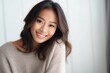 © Leon Waltz - medium shot portrait of a Filipino woman in her 30s wearing a cozy sweater against an abstract background