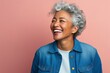 © Anne-Marie Albrecht - medium shot portrait of a happy Mexican woman in her 60s wearing a denim jacket against an abstract background