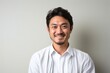 © Leon Waltz - portrait of a happy Japanese man in his 30s wearing a chic cardigan against a minimalist or empty room background