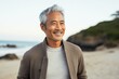 © Leon Waltz - portrait of a happy Japanese man in his 50s wearing a chic cardigan against a beach background