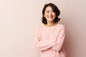 Wall Mural - medium shot portrait of a happy Japanese woman in her 40s wearing a cozy sweater against a pastel or soft colors background