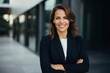 © Anne-Marie Albrecht - medium shot portrait of a happy Polish woman in her 30s wearing a sleek suit against a modern architectural background