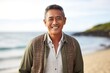 portrait of a Filipino man in his 50s wearing a chic cardigan against a beach background