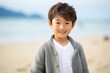 © Leon Waltz - portrait of a Japanese child male wearing a chic cardigan against a beach background