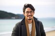 © Leon Waltz - portrait of a Japanese man in his 20s wearing a chic cardigan against a beach background