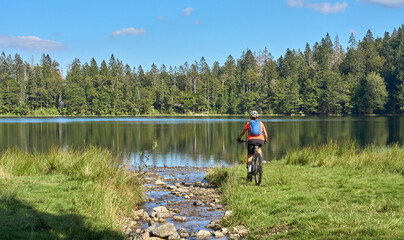 Wall Mural - nice senior woman on her electric mountain bike cycling Lake Feldsee in the  German Black Forest near Titisee-Neustadt, Baden-Württemberg, Germany