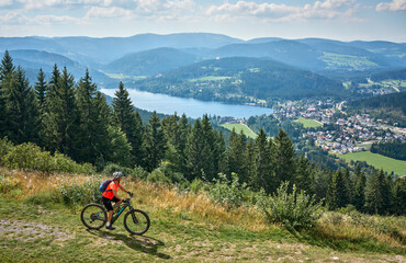 Wall Mural - nice senior woman on her electric mountain bike cycling in the German Black Forest above Lake Titisee, Baden-Württemberg, Germany