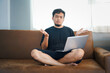 © NOTE OMG - People And Technology. Portrait Of Smiling Asian Man Holding And  Tablet Sitting On Couch Indoors In Living Room.