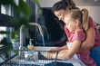 © lordn - A cute little girl helps her mother wash dishes. Child doing house chores. Mother teaches a child to wash dishes.