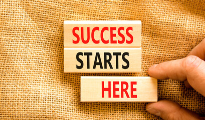 Wall Mural - Success starts here symbol. Concept word Success starts here on beautiful wooden block. Businessman hand. Beautiful canvas background. Business motivational success starts here concept. Copy space.