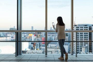 Wall Mural - Woman use mobile phone over the big window inside business office tower