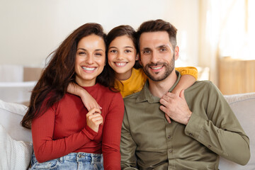 Cheerful arab father, mother and daughter posing embracing at home