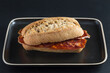 chorizo sandwich on dark tray, placed on black background