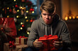 Displeased unhappy teenager unsatisfied with Christmas present. Boy grimacing skeptical holding gift box sitting near decorated Christmas tree at home