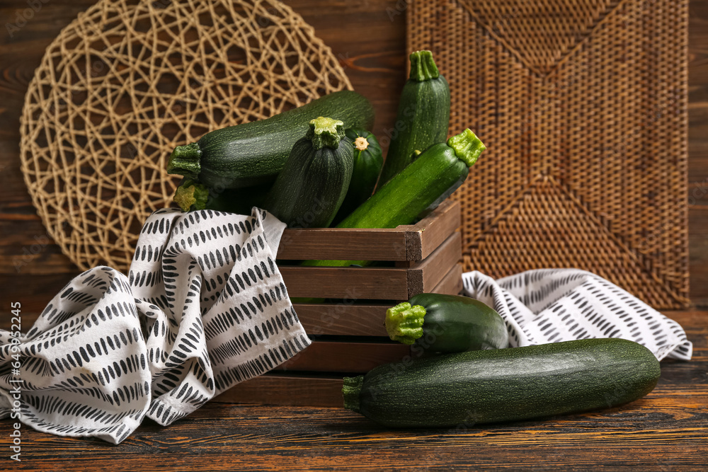 Box with many fresh zucchini on brown wooden background
