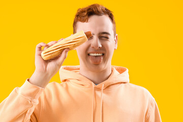 Canvas Print - Grimacing young man with tasty hot dog on yellow background