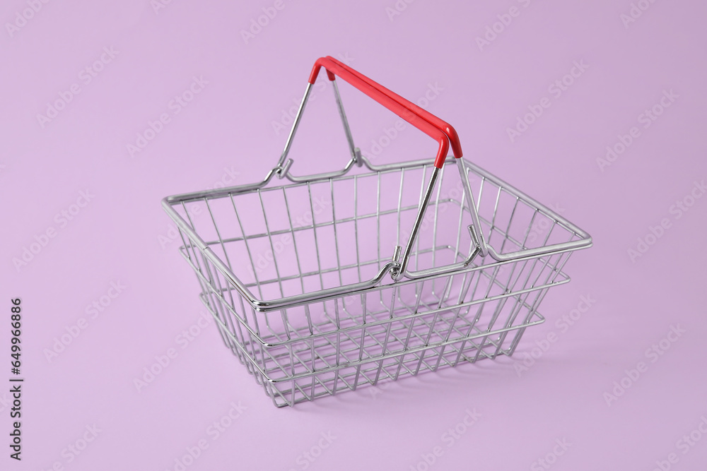Shopping basket on purple background, closeup