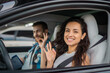 © Nataliya - Smiling young lady and male instructor showing ok sign while sitting in the car during studying in drive school. Driving test, driver courses, exam concept