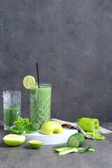 Glasses of healthy green juice with ingredients on grunge background