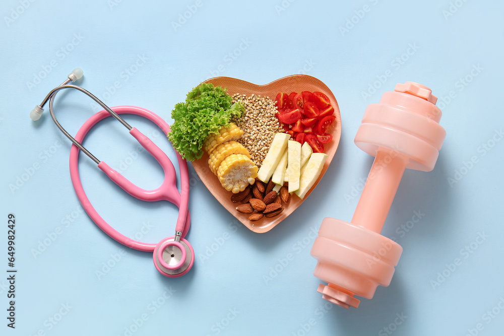 Plate with fresh healthy products, stethoscope and dumbbell on blue background. Diet concept