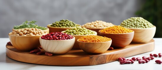 Wall Mural - Assorted legumes in wooden bowls on a light grey kitchen table suitable for vegetarians