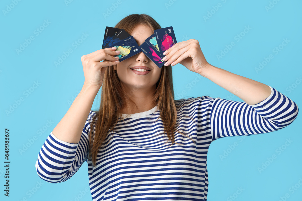 Young woman with credit cards on blue background