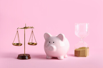 Piggy bank with scales of justice and sand glass on pink background