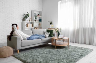 Poster - Beautiful young Asian woman relaxing on sofa in living room