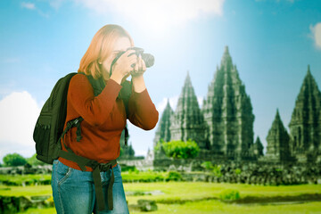 Young female photographer in casual winter clothes looking at viewfinder taking photos