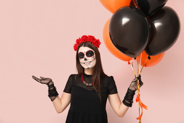 Wall Mural - Young woman dressed for Halloween with balloons on light background