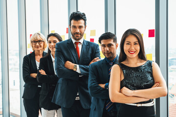 Wall Mural - Successful business people standing together showing strong relationship of worker community. A team of businessman and businesswoman expressing a strong group teamwork at the modern office. Jivy