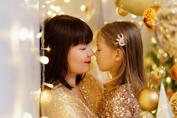 Wall Mural - Mother and daughter posing nose to nose in christmas decorations