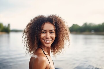 shot of a beautiful young woman standing on her paddleboard and smiling at the camera