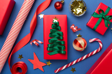 Wall Mural - Gift boxes with paper's rools and christmas decoration on color background, top view