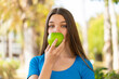 Teenager girl at outdoors holding an apple