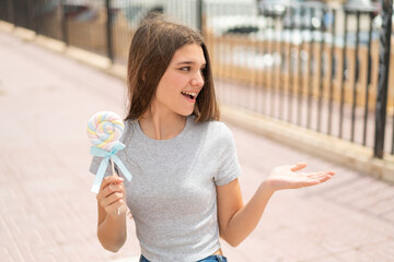 Sticker - Teenager girl holding a lollipop with surprise facial expression