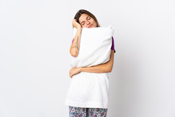 Young slovak woman isolated on white background in pajamas and holding a pillow while sleeping