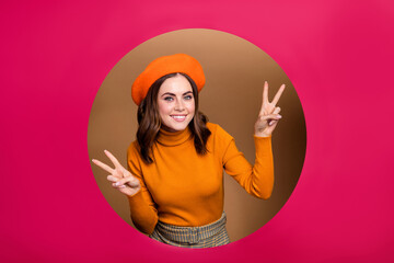 Wall Mural - Photo of cheerful joyful lady peek out pink paper hole wear trendy clothes two arm demonstrate v-sign isolated on beige color background