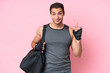 © luismolinero - Young sport caucasian man with sport bag isolated on pink background pointing with the index finger a great idea