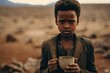 African child close-up with an empty iron mug against the backdrop of a dry river bed. Drought, water shortage problem.