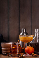 Wall Mural - Maple syrup autumn cocktails. Boozy strong alcohol, non-alcoholic mocktail drinks with apple cider, liqueur and spices, on dark wooden background copy space