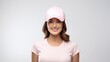 © Pro Hi-Res - Pretty young woman smiling and wearing pink baseball cap against a white wall background.