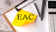EAC word on yellow sticky with calculator, pen and clipboard