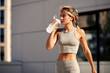 © Georgii - Maintaining hydration. A woman drinks water during a workout, replenishing her water-salt balance, beautiful light, a woman quenches her thirst on a sunny day