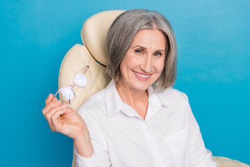 Sticker - Photo of clever smiling woman dressed white shirt sitting chair holding spectacles isolated blue color background